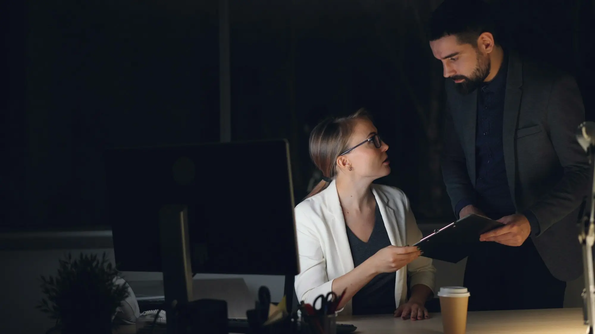Two colleagues going over a document together at a desk in a quiet office.