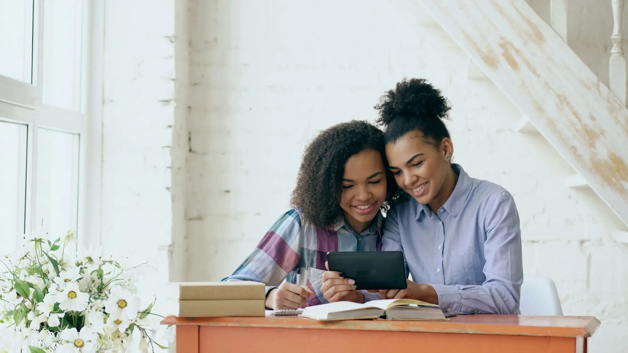 Two business partners sitting close at a table, reviewing paperwork together.