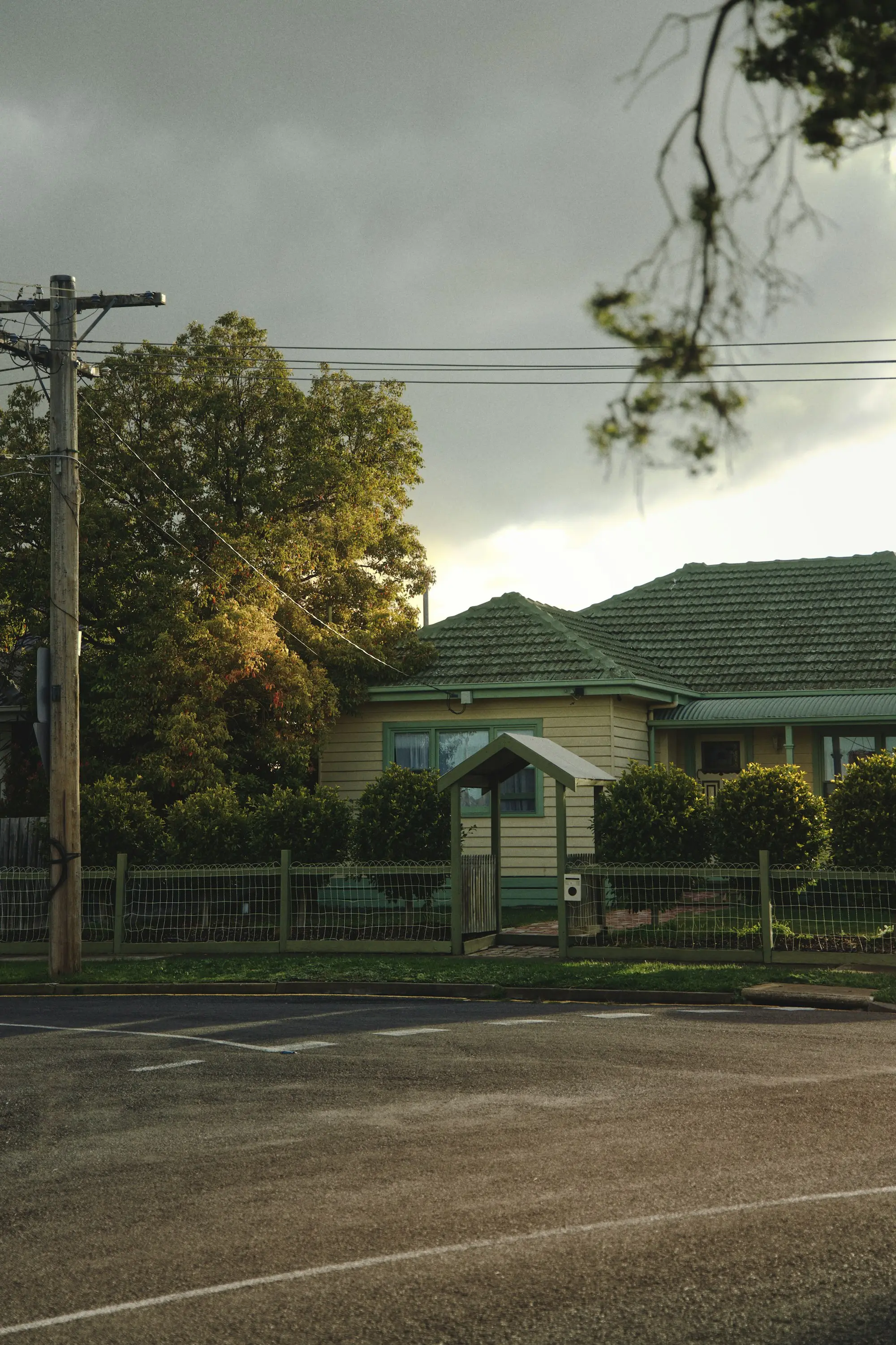 Suburban house with a pitched roof surrounded by green trees on a clear day.