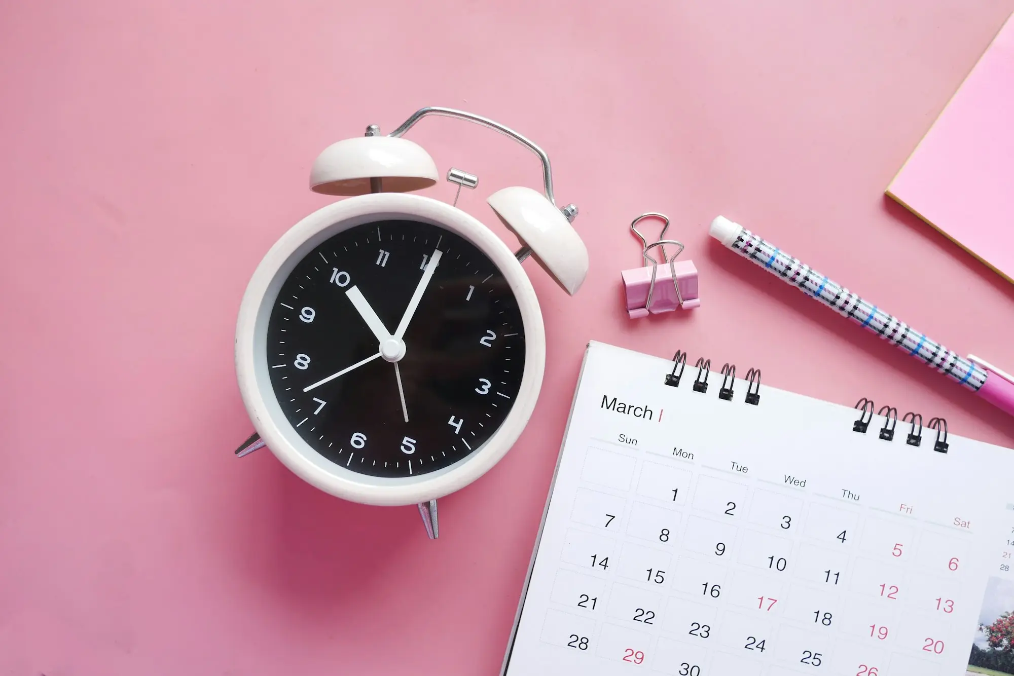 Alarm clock beside a desk calendar and paper clip, a reminder that loan documents have a shelf life before you lodge
