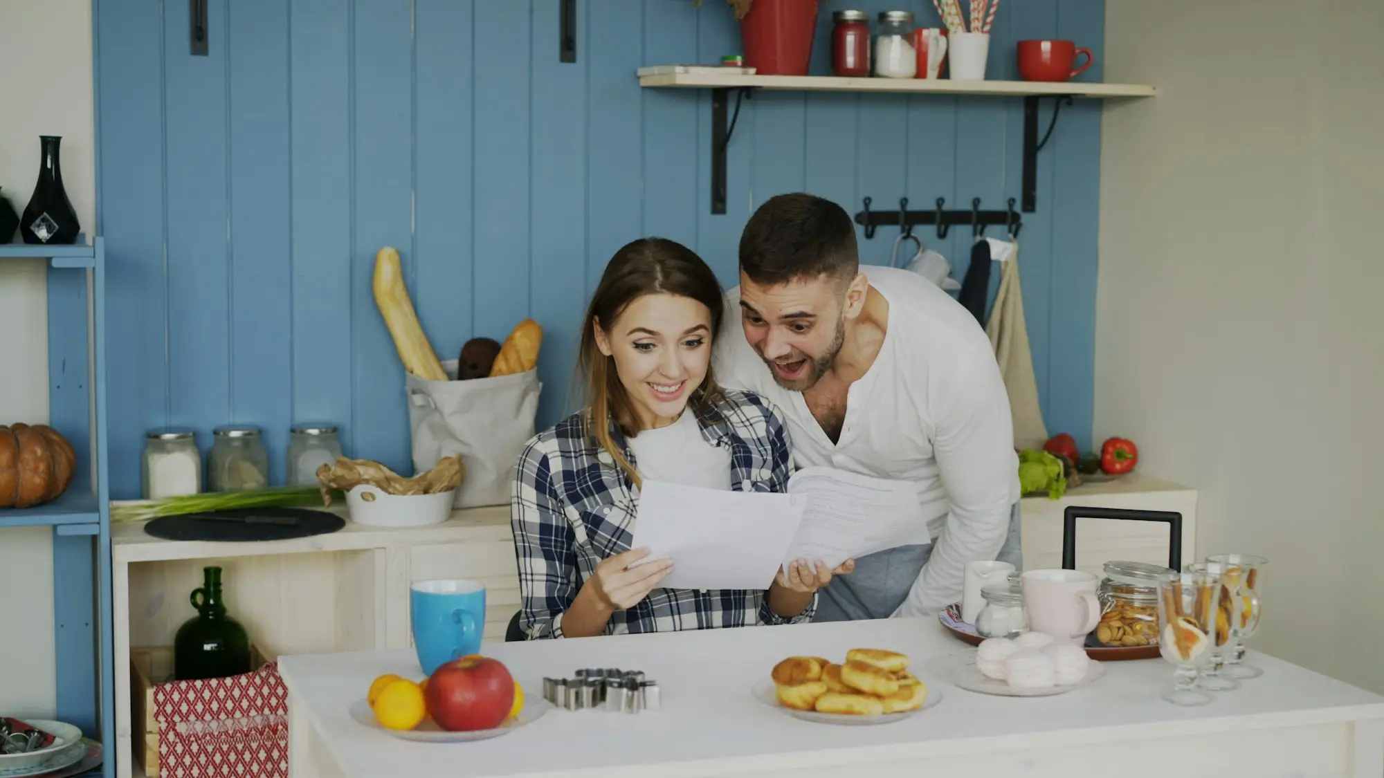 Couple looking over papers together at a bright kitchen table.